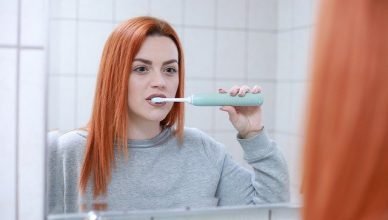 chica limpiándose los dientes con un cepillo eléctrico